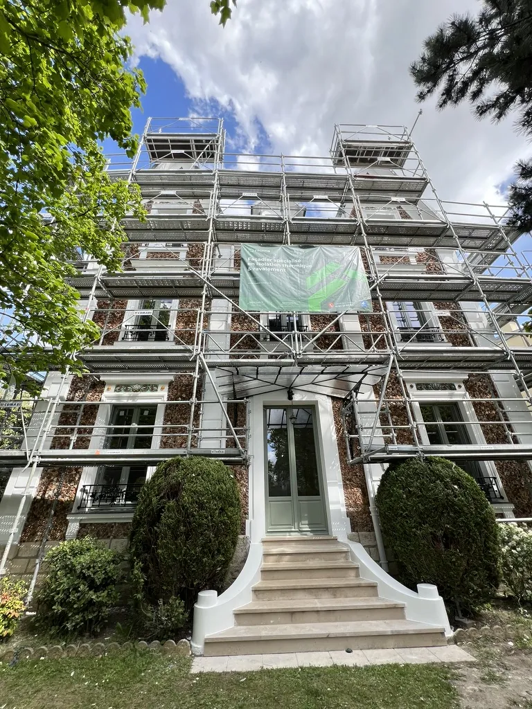Large millstone house under scaffolding during its facade work