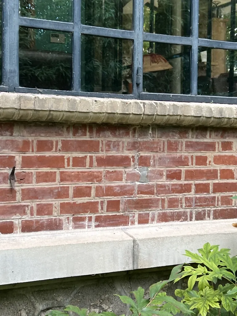 Soubassement en brique sous une verrière d’atelier, avant : briques salies, joints usés