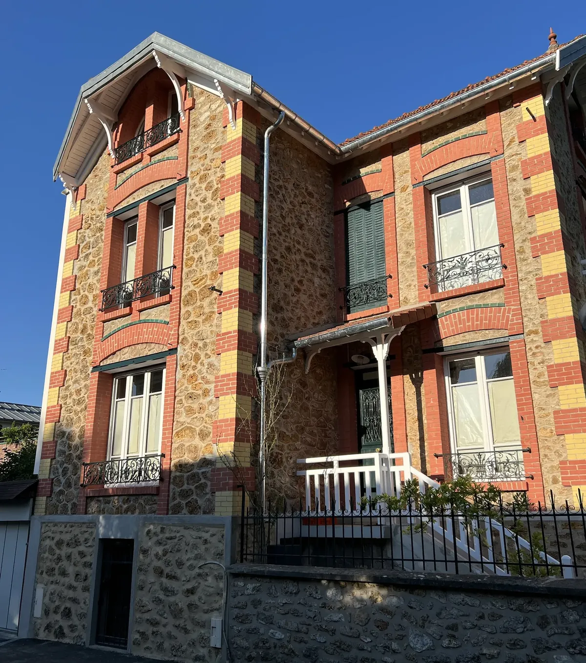 Villa en meulière apparente, chaînes d’angle en brique rouge et jaune, bandeaux de brique vernissée